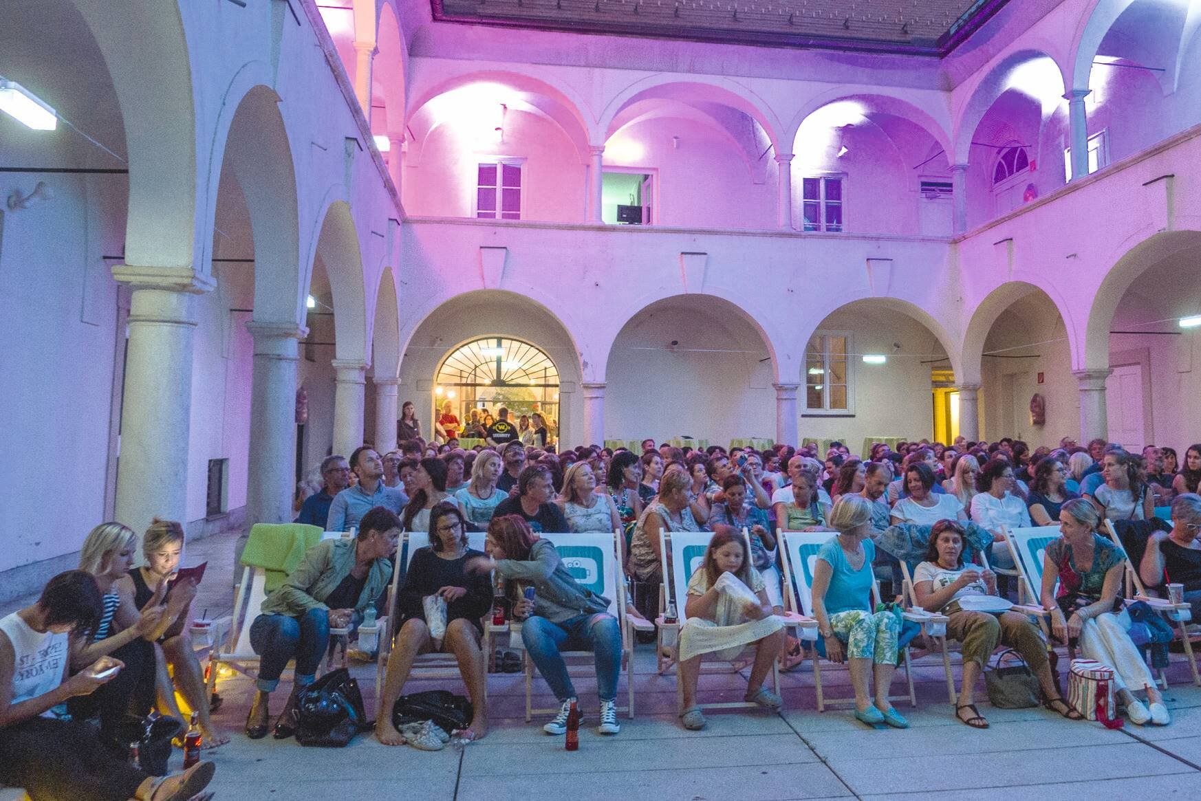 Kinobesucher:innen im Arkadenhof des Open-Air Kinos in Villach