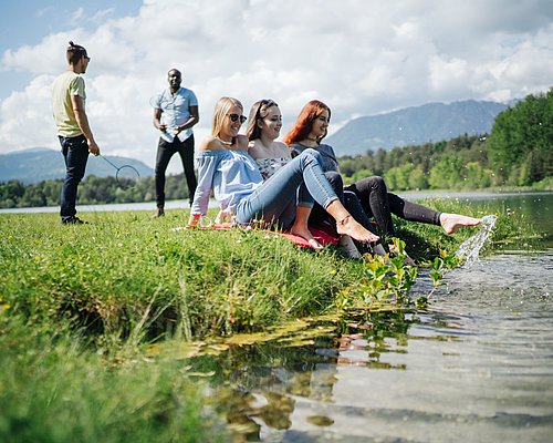Studierende sitzen in der Wiese am Fluss
